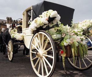 A wedding carriage drawn by four horses, waiting outside the church.